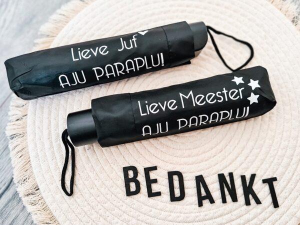 Zwarte opvouwbare paraplu bedrukt met de tekst: Lieve juf / meester, Aju Paraplu.