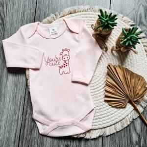 Roze romper bedrukt met een giraffe en de tekst: You're cute.