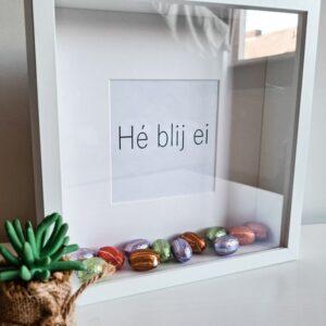 Houten witte fotolijst met de tekst: Hé blij ei en gevuld met paaseieren