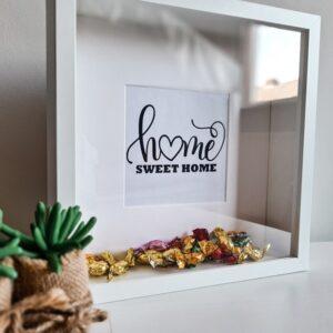 Houten witte fotolijst met de tekst: Home sweet home. De lijst is gevuld met snoepjes.
