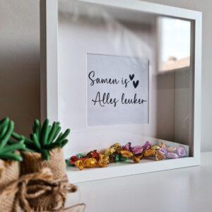 Houten witte fotolijst met de tekst: Samen is alles leuker. De lijst is gevuld met snoepjes.