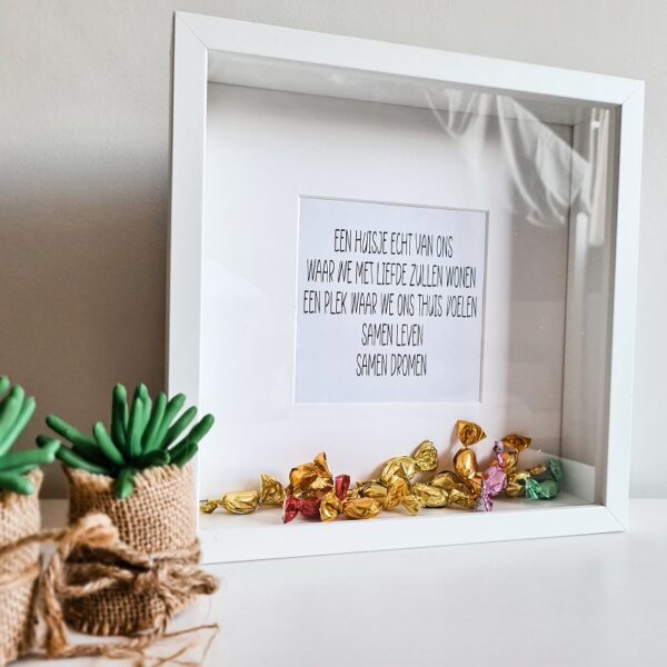 Houten witte fotolijst met de tekst over samenwonen. De lijst is gevuld met snoepjes.
