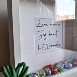 Houten witte fotolijst met de tekst: Jij bent bEIzonder en gevuld met paaseieren
