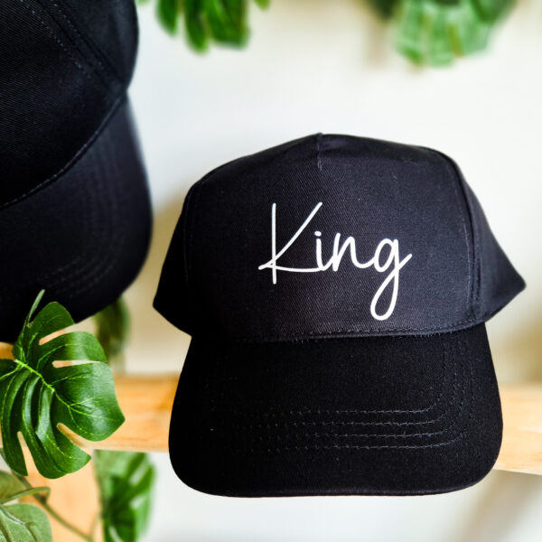 Detailfoto van zwarte, unisex pet bedrukt met de tekst 'King'.