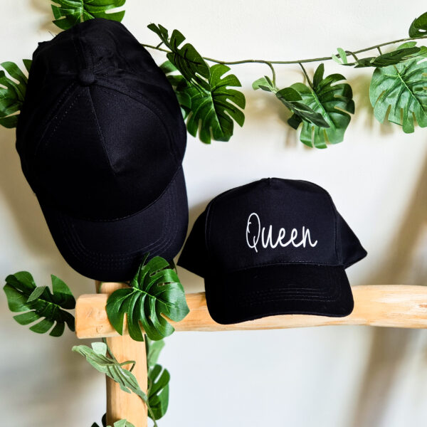 Zwarte, unisex pet bedrukt met de tekst 'Queen'.