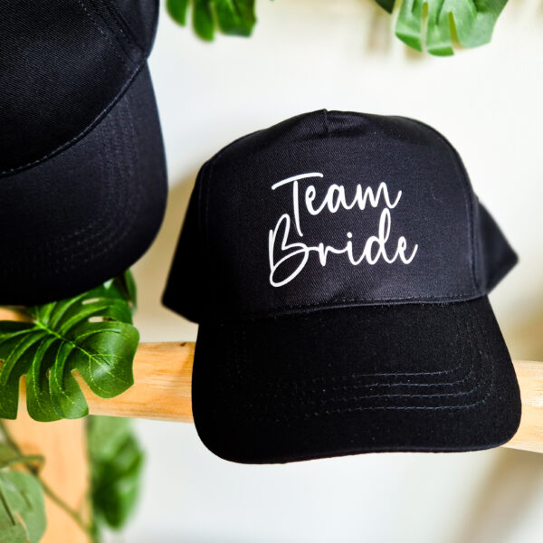 Detailfoto van zwarte, unisex pet bedrukt met de tekst 'Team Bride'.
