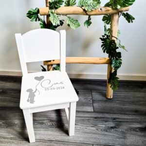 Witte houten kinderstoel met een jongen die een ballon vasthoudt en naam en geboortedatum.