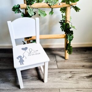 Witte houten kinderstoel met een meisje die een ballon vasthoudt en naam en geboortedatum.