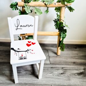 Witte houten kinderstoel met uiltjes in een boom en de naam op de rugleuning.