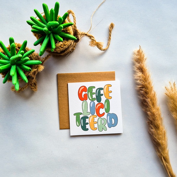 Een dubbelzijdige verjaardagskaart met de kleurrijke tekst Gefeliciteerd. Geschreven in vrolijke handlettering.