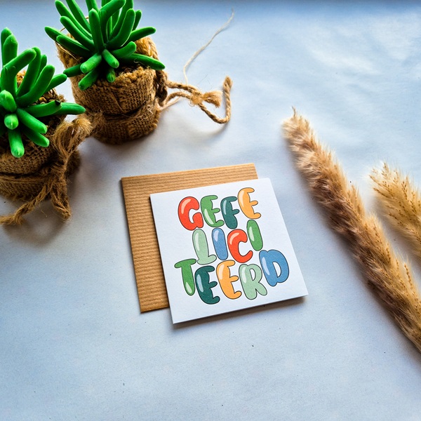 Een dubbelzijdige verjaardagskaart met de kleurrijke tekst Gefeliciteerd. Geschreven in vrolijke handlettering.